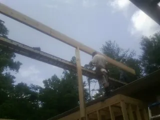 Carpenter setting a ridge beam over a new addition frame — Ice Dam Removal by Roofing Brothers in Cape Charles
