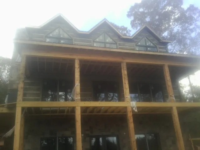 Dormers and porch framing on a large log home under construction — Roof Coating work by our crew in Cape Charles