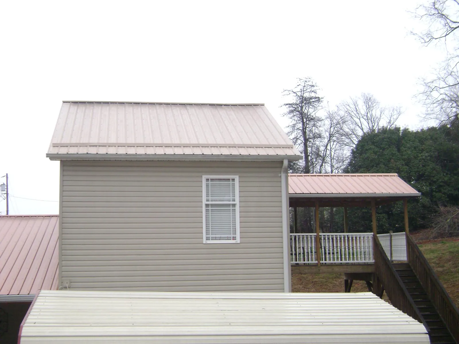 Tan metal roofs on a two story addition and attached porch, from a Roof Replacement job in Cape Charles