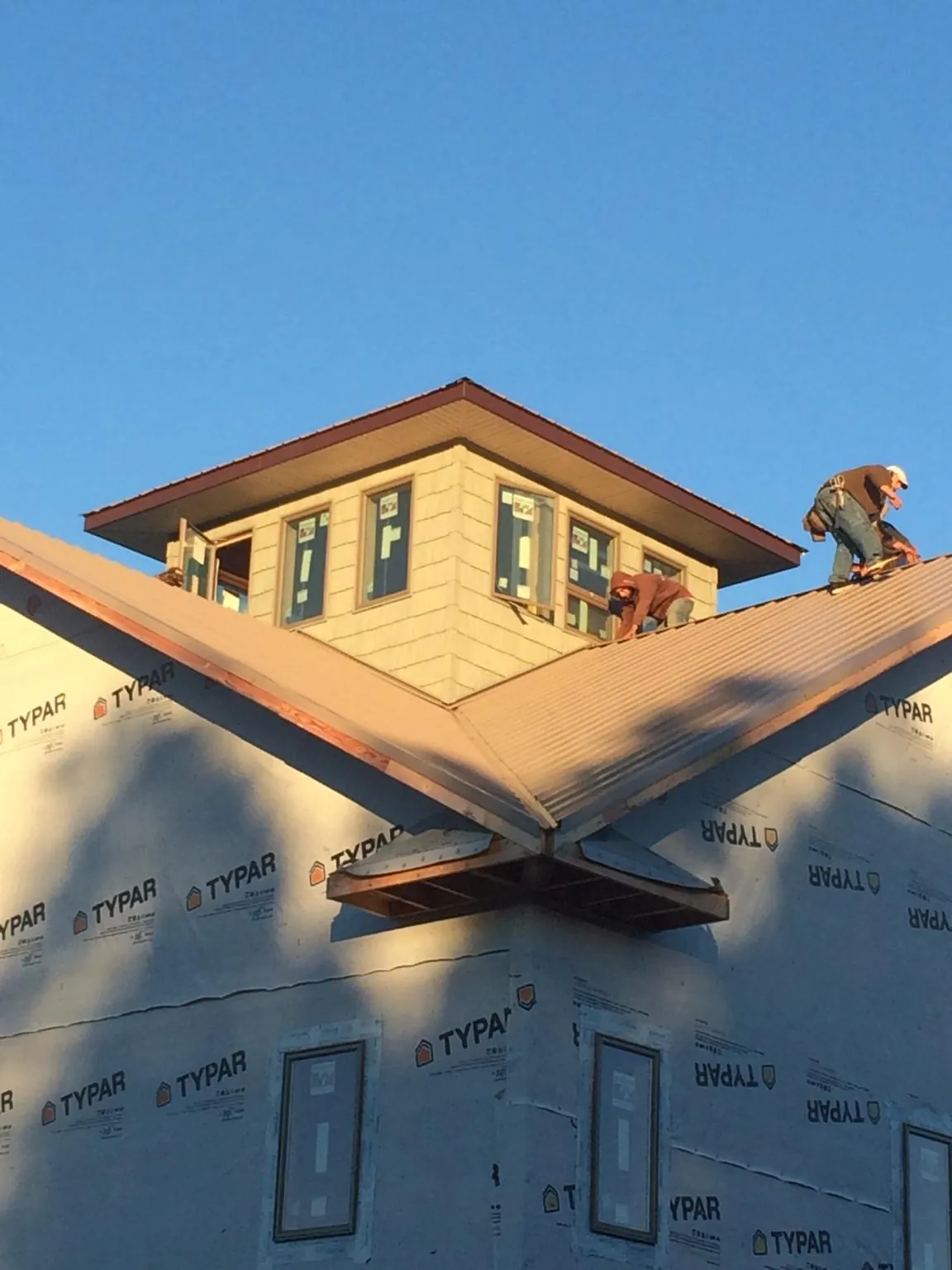 Roofers working around a rooftop cupola on a new metal roof at sunset — Roof Waterproofing in Cape Charles by Roofing Brothers